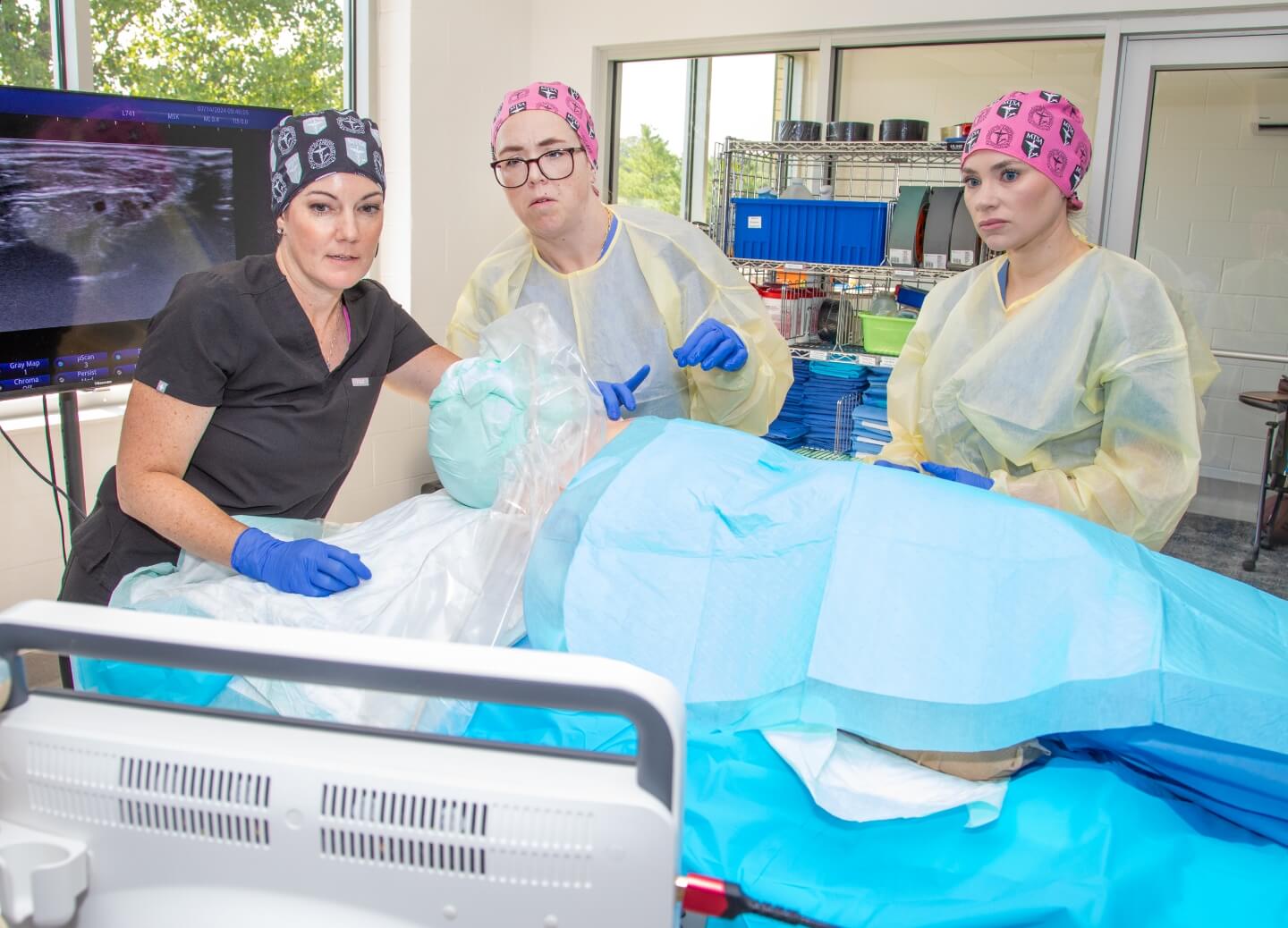 Students learning in the cadaver lab while professor demonstrates a skill