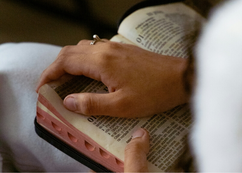 person resting their hand on an open bible