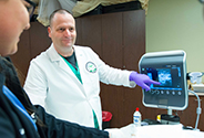 CRNA pointing at ultrasound monitor with student watching and smiling