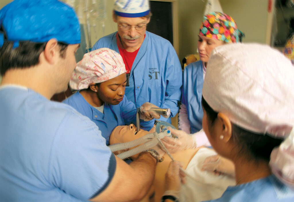 CRNA student incubating mannequin with peers surrounding her